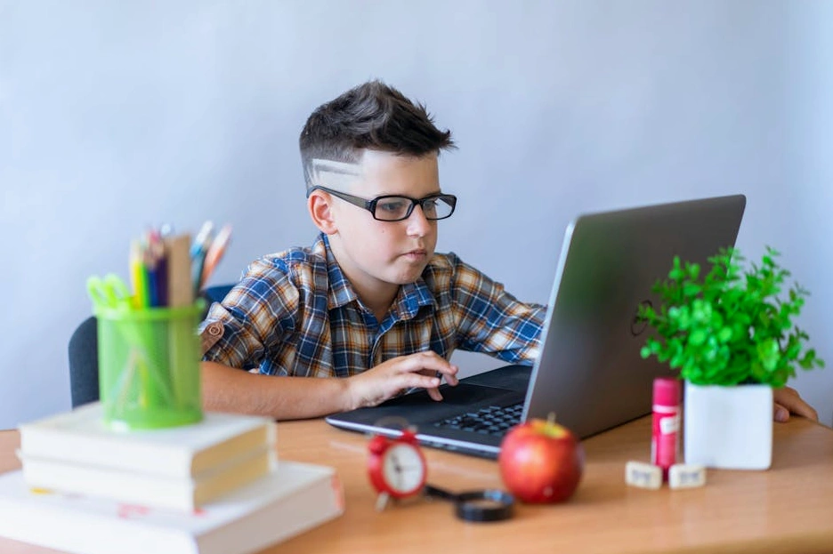 Studente sorridente che utilizza un laptop in una biblioteca moderna.